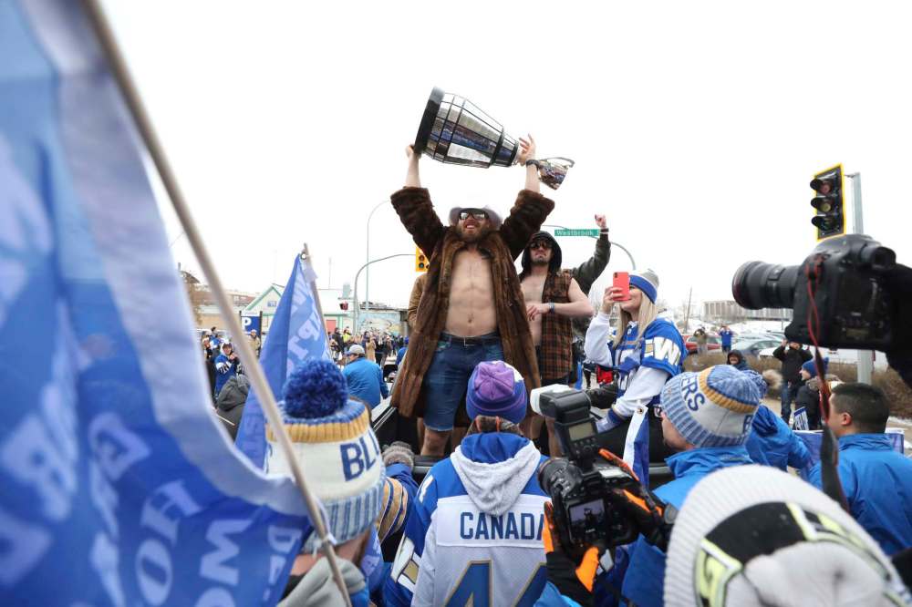 Quarterback Chris Streveler hoists the Grey Cup during Tuesday's parade. The city and the Winnpeg Football Club have committed funding the celebration, but the costs are still being calculated. (Ruth Bonneville / Winnipeg Free Press)