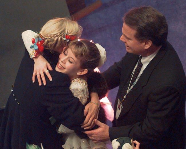 FILE - In this Saturday, Feb. 15, 1997 file photo, figure skater Tara Lipinski with her coach Richard Callaghan receives a hug after it was announced she won the gold medal at the U.S. Figure Skating Championships in Nashville, Tenn. Richard Callaghan, who coached Tara Lipinski to Olympic gold, has been banned from figure skating by the U.S. Center for SafeSport for sexual misconduct. (AP Photo/Cliff Schiappa, File)
