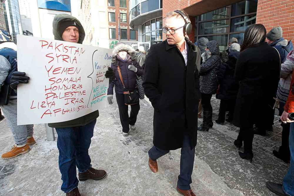 JOHN WOODS / WINNIPEG FREE PRESS
A demonstrator, left, hands out brochures as he protests the Barack Obama speech outside Bell MTS Place Monday.