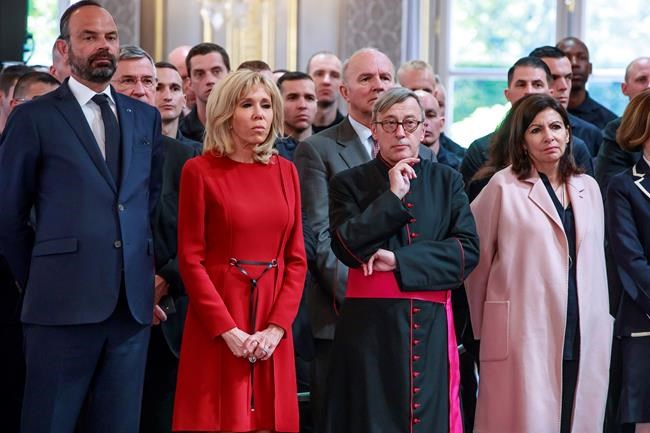 French Prime Minister Edouard Philippe, left, French President 's wife Brigitte Macron, second left, Archibishop of Paris Jean-Marc Chauvet and Paris mayor Anne Hidalgo listen to French President Emmanuel Macron addressing Paris Firefighters' brigade and security forces who took part at the fire extinguishing operations of the Notre Dame of Paris Cathedral fire, at the Elysee Palace in Paris, Thursday, April 18, 2019. France paid a daylong tribute Thursday to the Paris firefighters who saved the internationally revered Notre Dame Cathedral from collapse and rescued many of its treasures.(Christophe Petit Tesson, Pool via AP)