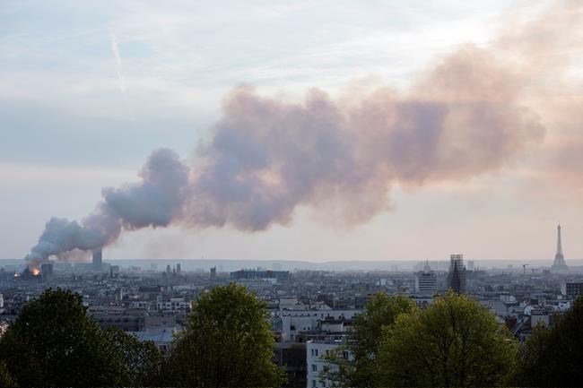 Smoke fill the air as Notre Dame cathedral is burning in Paris, Monday, April 15, 2019. Massive plumes of yellow brown smoke is filling the air above Notre Dame Cathedral and ash is falling on tourists and others around the island that marks the center of Paris. (AP Photo/Rafael Yaghobzadeh)