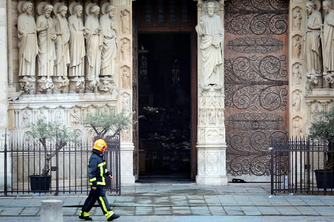 A firefighter walks in front of Notre Dame cathedral Tuesday April 16, 2019 in Paris. Firefighters declared success Tuesday morning in an over 12-hour battle to extinguish an inferno engulfing Paris' iconic Notre Dame cathedral that claimed its spire and roof, but spared its bell towers. (Ludovic Marin via AP)