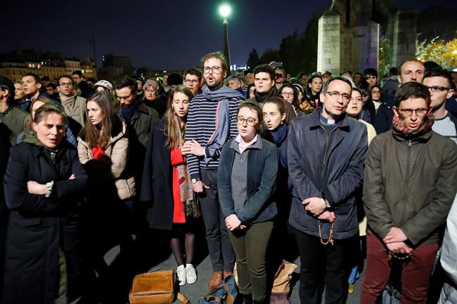 People pray as Notre Dame cathedral is burning in Paris, Monday, April 15, 2019. A catastrophic fire engulfed the upper reaches of Paris' soaring Notre Dame Cathedral as it was undergoing renovations Monday, threatening one of the greatest architectural treasures of the Western world as tourists and Parisians looked on aghast from the streets below. (AP Photo/Francois Mori)