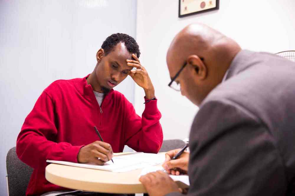 Yahya Samatar talks to his lawyer, Bashir Khan, at the Welcome Place in Winnipeg on Wednesday. (Mikaela MacKenzie / Winnipeg Free Press)