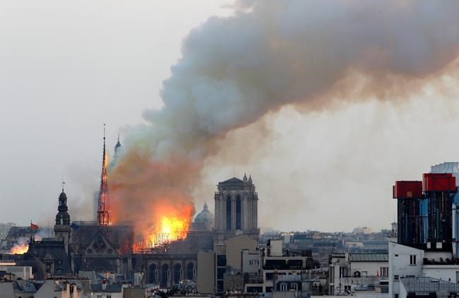 Flames rise from Notre Dame cathedral as it burns in Paris, Monday, April 15, 2019. Massive plumes of yellow brown smoke is filling the air above Notre Dame Cathedral and ash is falling on tourists and others around the island that marks the center of Paris. (AP Photo/Thibault Camus)