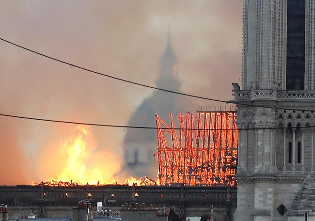 Flames rise from Notre Dame cathedral as it burns in Paris, Monday, April 15, 2019. Massive plumes of yellow brown smoke is filling the air above Notre Dame Cathedral and ash is falling on tourists and others around the island that marks the center of Paris. (AP Photo/Thibault Camus)
