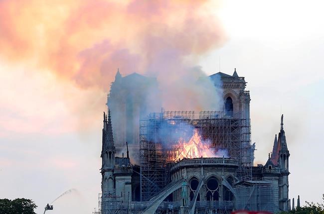 A firefighter tackles the blaze as flames and smoke rise from Notre Dame cathedral as it burns in Paris, Monday, April 15, 2019. Massive plumes of yellow brown smoke is filling the air above Notre Dame Cathedral and ash is falling on tourists and others around the island that marks the center of Paris. (AP Photo/Thibault Camus)