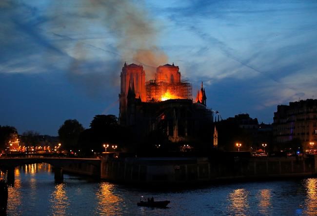 Firefighters tackle the blaze as flames and smoke rise from Notre Dame cathedral as it burns in Paris, Monday, April 15, 2019. Massive plumes of yellow brown smoke is filling the air above Notre Dame Cathedral and ash is falling on tourists and others around the island that marks the center of Paris. (AP Photo/Michel Euler)