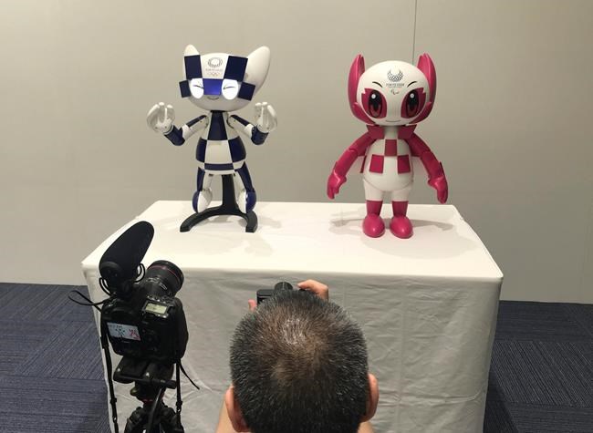 In this Thursday, July 18, 2019, photo, a journalist takes a photo of robots of mascots of Olympics