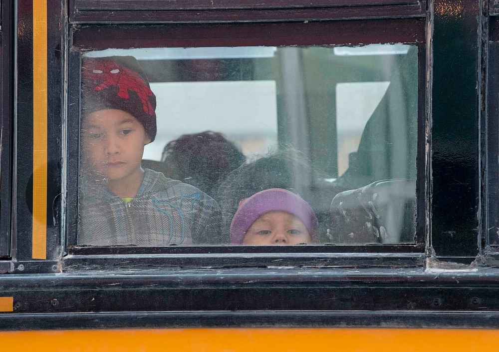 Two evacuated children from the Lake Manitoba First Nation sit on a bus outside a hotel in Winnipeg on Monday. (Adrian Wyld / The Canadian Press)