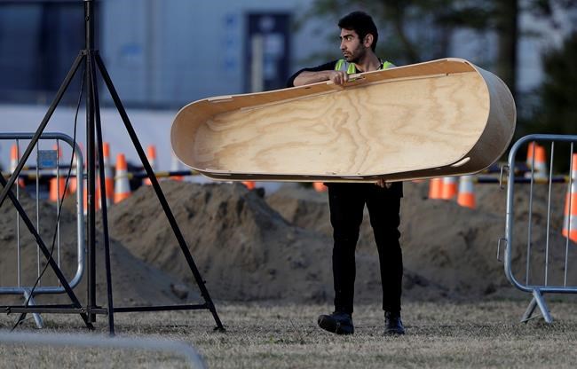 A worker carries a coffin away from the grave site of a victim in the Friday, March 15, mosque shootings for burial at the Memorial Park Cemetery in Christchurch, New Zealand, Wednesday, March 20, 2019. (AP Photo/Mark Baker)