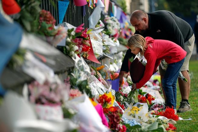Mourners lays flowers on a wall at the Botanical Gardens in Christchurch, New Zealand, Saturday, March 16, 2019. New Zealand's stricken residents reached out to Muslims in their neighborhoods and around the country on Saturday, in a fierce determination to show kindness to a community in pain as a 28-year-old white supremacist stood silently before a judge, accused in mass shootings at two mosques that left dozens of people dead. (AP Photo/Vincent Thian)