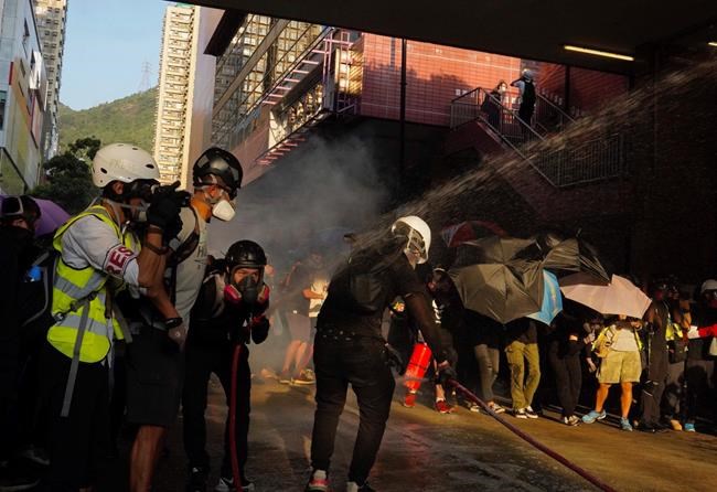 Protesters hide behind umbrellas during a confrontation with police Saturday, Sept. 21, 2019, in Hong Kong. Demonstrators have marched through an outlying district of Hong Kong in another weekend of protest aimed at the Chinese territory's government. (AP Photo/Vincent Yu)