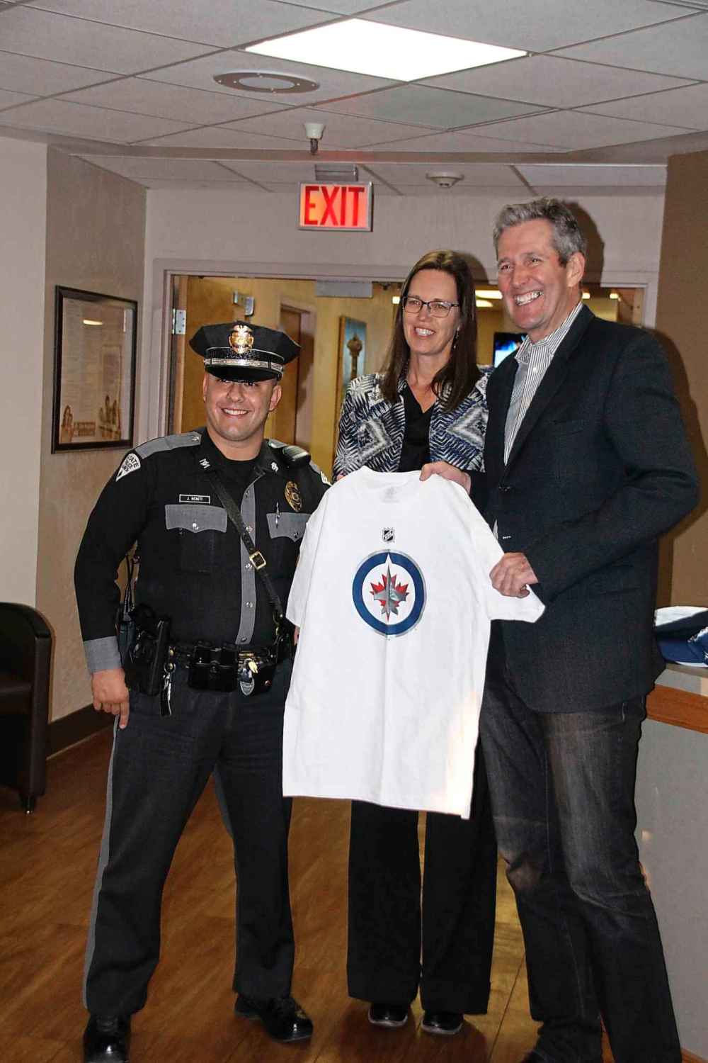 Mary Alice Murphy / Grant County Beat
New Mexico State Patrolman Justin McNett, who first rescued Premier Pallister, accepts a Winnipeg Jets t-shirt from Pallister and his wife, Esther.