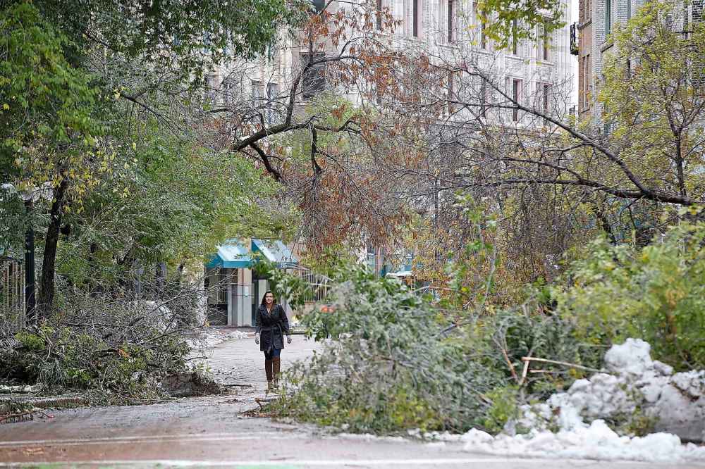 A pedestrian makes her way through some tree branches on Albert Street following an early season snowstorm in October. (John Woods / Free Press files)