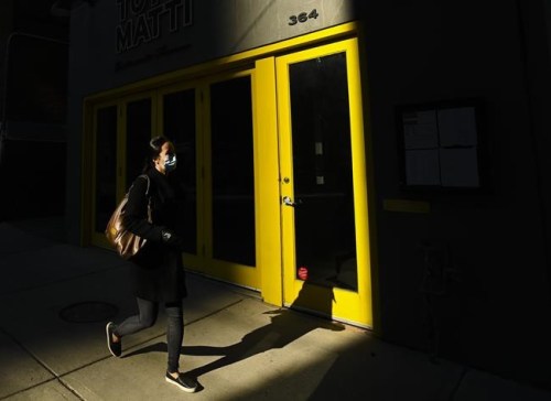 A woman wearing a protective mask walks through a shaft of light during the COVID-19 pandemic in downtown Toronto on Thursday, November 12, 2020. nbsp;The COVID-19 case count continues to climb at an alarming pace west of the Maritimes, despite tighter restrictions as some jurisdictions gird for more drastic measures. THE CANADIAN PRESS/Nathan Denette