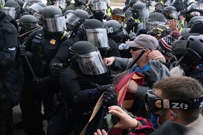 Capitol police officers in riot gear push back demonstrators who try to break a door of the U.S. Capitol on Wednesday, Jan. 6, 2021, in Washington. Prime Minister Justin Trudeau is again condemning violent rioters he says were incited by U.S. President Donald Trump and other politicians on Capitol Hill this week. THE CANADIAN PRESS/AP/Jose Luis Magana