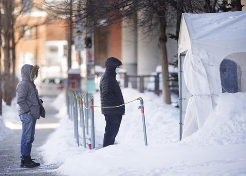 People wear face masks as they wait to be tested for COVID-19 at a clinic in Montreal, Sunday, January 31, 2021, as the COVID-19 pandemic continues in Canada and around the world. THE CANADIAN PRESS/Graham Hughes