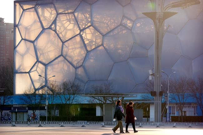 People walk past the Water Cube, which will be known as the Ice Cube when it hosts events for the 2022 Beijing Winter Olympics, in Beijing, Tuesday, Feb. 2, 2021. Canada will not boycott the 2022 Winter Games in Beijing despite calls from human rights organizations to do so. THE CANADIAN PRESS/AP/Mark Schiefelbein