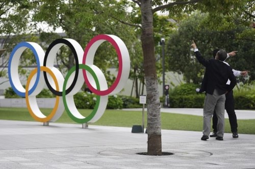 Men gesture near the Olympic Rings Wednesday, June 2, 2021, in Tokyo. (AP Photo/Eugene Hoshiko)