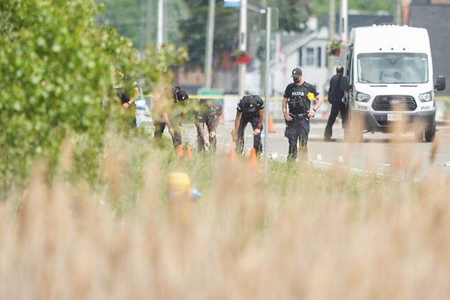 A line of police officers look for evidence at the scene of a car crash in London, Ont., on Monday, June 7, 2021. London police in London say four people have died after several pedestrians were struck by a car Sunday night.THE CANADIAN PRESS/Geoff Robins
