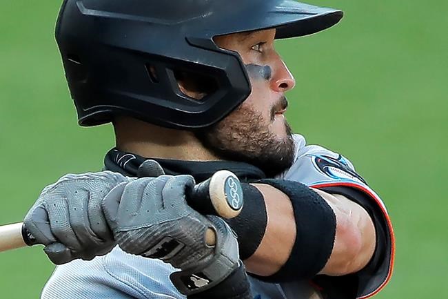 FILE - The Olympic rings are seen on the knob of Miami Marlins' Eddy Alvarez's bat as he swings at a pitch from the Baltimore Orioles during the seventh inning in the first game of a baseball doubleheader in Baltimore, in this Wednesday, Aug. 5, 2020, file photo. Alvarez, having won a silver in speed skating at Sochi in 2014, helped the U.S. reach the Olympic baseball tournament and could become only the third American to win medals at the summer and winter Games. (AP Photo/Julio Cortez, File)