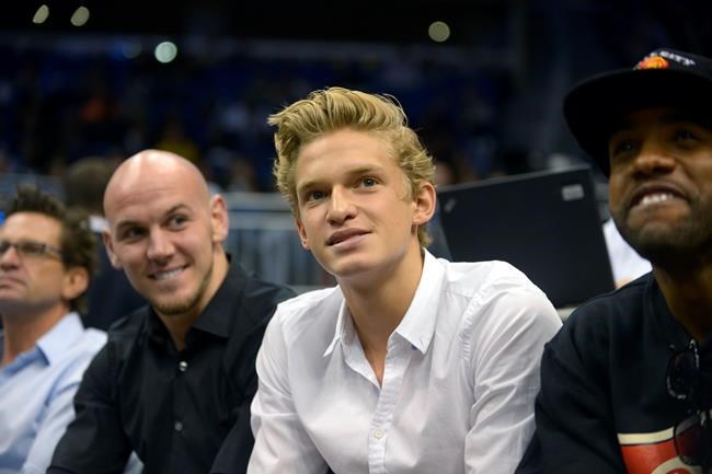 Singer Cody Simpson, second from right, watches an Orlando Magic game from his court-side seats during the first half of an NBA basketball game against the Toronto Raptors in Orlando, Fla., Thursday, Jan. 24, 2013. Simpson was dominating attention ahead of Australia’s Olympic swimming trials, until Maddie Groves pulled out of the six-day meet following a series of social media posts condemning “misogynistic perverts” in the sport.(AP Photo/Phelan M. Ebenhack)