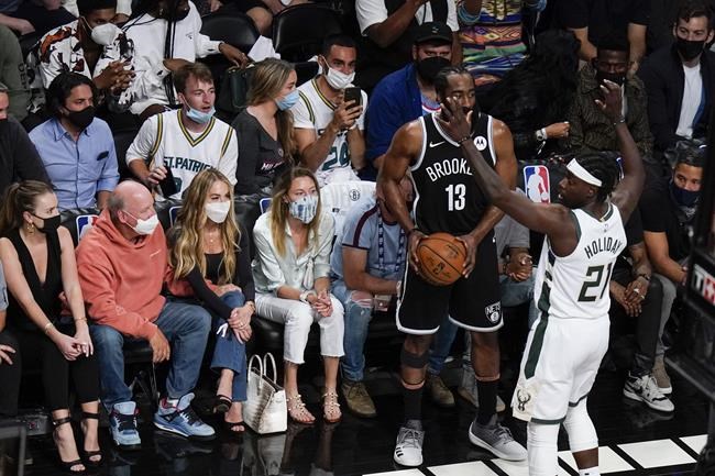 Fans watch as Milwaukee Bucks' Jrue Holiday (21) defends against Brooklyn Nets' James Harden (13) during the first half of Game 7 of a second-round NBA basketball playoff series Saturday, June 19, 2021, in New York. (AP Photo/Frank Franklin II)