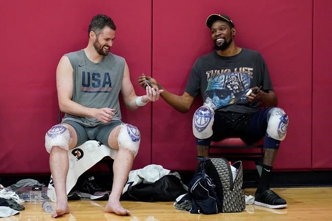 Kevin Love, left, and Kevin Durant laugh while passing a cell phone after practice for USA Basketball, Wednesday, July 7, 2021, in Las Vegas. (AP Photo/John Locher)