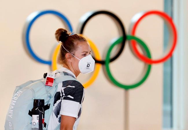 A German athlete wearing a face mask walks past the Olympic rings display on their arrival at Haneda airport in Tokyo on Thursday, July 1, 2021. THE CANADIAN PRESS/Kyodo News via AP