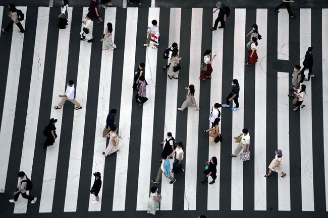People wearing protective masks to help curb the spread of the coronavirus walk along a pedestrian crossing Thursday, July 22, 2021, in Tokyo. The Japanese capital confirmed more than 1900 new coronavirus cases on Thursday. (AP Photo/Eugene Hoshiko)