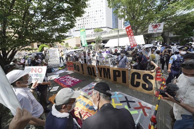 Anti-Olympics protestors hold signs during a rally near the Tokyo Metropolitan Government complex where the final Olympic torch relay event took place in Tokyo Friday, July 23, 2021. The opening ceremony of the Tokyo Olympics is scheduled later Friday. (AP Photo/Kantaro Komiya)