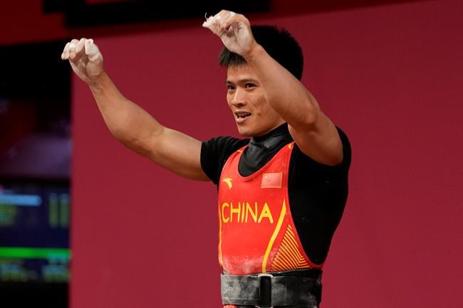 Li Fabin of China celebrates after a lift as he competes in the men's 61kg weightlifting event, at the 2020 Summer Olympics, Sunday, July 25, 2021, in Tokyo, Japan. (AP Photo/Luca Bruno)