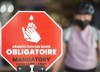 People wear face masks as they walk by a sign reading 