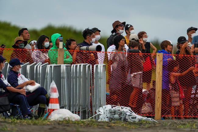 People watch from behind a security fence during the final day of the surfing competition at the 2020 Summer Olympics, Tuesday, July 27, 2021, at Tsurigasaki beach in Ichinomiya, Japan. The Olympic beach party that never was may be the only sore spot for surfing’s long-awaited debut that finished triumphantly this week. Some local Japanese fans and beachgoers did manage to find a way to lay eyes on the athletes and the competition site once the games began. (AP Photo/Francisco Seco)