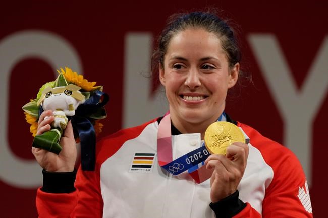 Maude Charron of Canada celebrates her gold medal on the podium of the women's 64kg weightlifting event, at the 2020 Summer Olympics, Tuesday, July 27, 2021, in Tokyo, Japan. THE CANADIAN PRESS/AP/Luca Bruno
