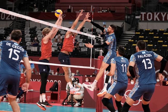 Argentina's Facundo Conte spikes a ball past Maxwell Holt, #12, and Taylor Sander, of the United States, during a men's volleyball preliminary round pool B match, at the 2020 Summer Olympics, early Monday, Aug. 2, 2021, in Tokyo, Japan. (AP Photo/Manu Fernandez)