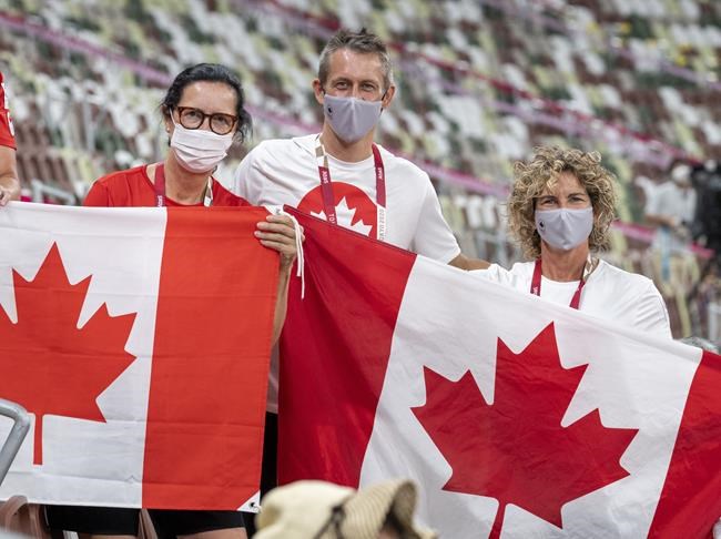 Canadian Olympic Association President Tricia Smith, CEO David Shoemaker and Team Canada Chef de Mission Marnie McBean hold Canadian flags during medal ceremonies at the Tokyo Olympics in Tokyo, Japan on Saturday August 7, 2021. THE CANADIAN PRESS/ Frank Gunn