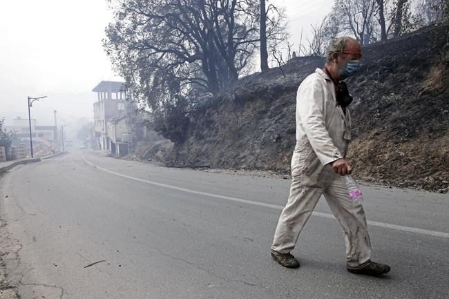 A man leaves a village near Tizi Ouzou some 100 km (62 miles) east of Algiers following wildfires in this mountainous region, Tuesday, Aug.10, 2021. Firefighters were battling a rash of fires in northern Algeria that have killed at least six people in the mountainous Kabyle region, the interior minister said Tuesday, accusing