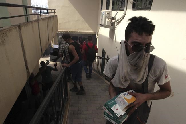A man saves drugs in a small hospital as residents evacuate a village near Tizi Ouzou some 100 km (62 miles) east of Algiers following wildfires in this mountainous region, Tuesday, Aug.10, 2021. Firefighters were battling a rash of fires in northern Algeria that have killed at least six people in the mountainous Kabyle region, the interior minister said Tuesday, accusing