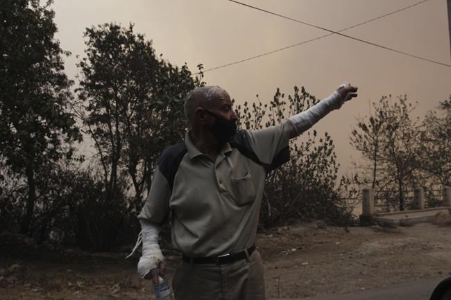 A man flees a village near Tizi Ouzou some 100 km (62 miles) east of Algiers following wildfires in this mountainous region, Tuesday, Aug.10, 2021. Firefighters were battling a rash of fires in northern Algeria that have killed at least six people in the mountainous Kabyle region, the interior minister said Tuesday, accusing