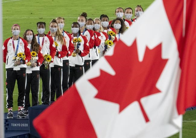 Members of the Canadian women’s soccer team watch the flag rise after being presented with their gold medals at the Tokyo Olympics in Tokyo, Japan on Friday August 6, 2021. The CBC is touting record-breaking digital audiences for the 2020 Tokyo Olympics, while television viewership ranked it the most-watched network in Canada throughout the Games. THE CANADIAN PRESS/ Frank Gunn