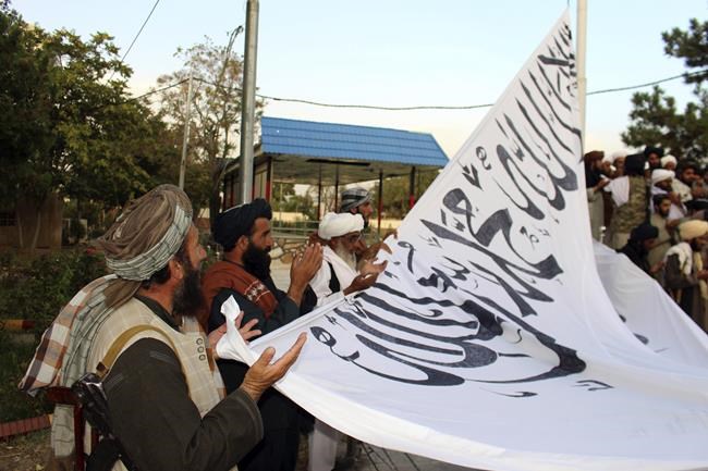 Taliban fighters pray while raising their flag at the Ghazni provincial governor's house, in Ghazni, southeastern, Afghanistan, Sunday, Aug. 15, 2021. (AP Photo/Gulabuddin Amiri)