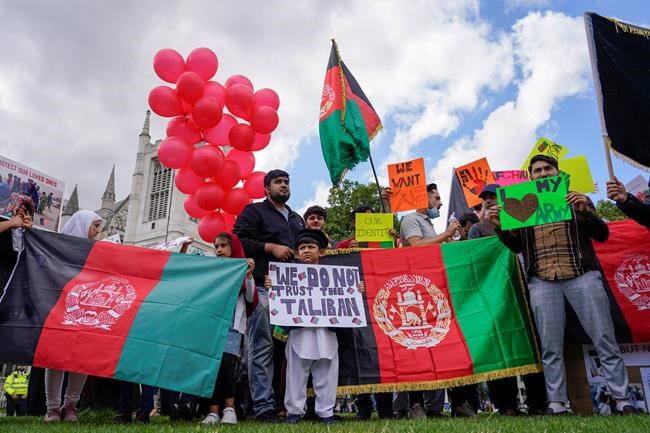 Demonstrators hold Afghanistan flags, during a protest in Parliament Square, London, Wednesday, Aug. 18, 2021. Britain’s government says it plans to take in 5,000 Afghan refugees this year, especially women and children, in response to the Taliban's seizure of power. Officials provided details about the resettlement program on Wednesday as lawmakers held a heated emergency debate on developments in Afghanistan. (AP Photo/Alberto Pezzali)