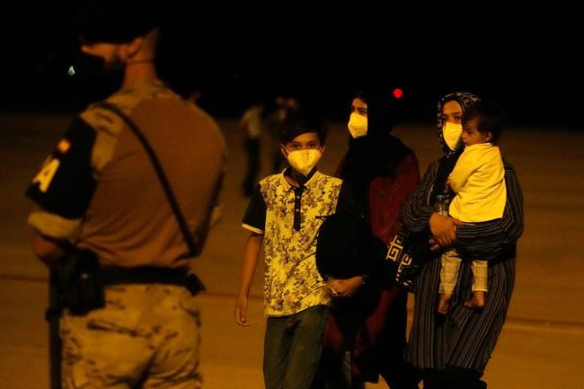 Afghans pass a Spanish soldier after arriving on a Spanish Air Force plane carrying Spanish nationals and Afghans at the Torrejon military base as part of the evacuation process in Madrid, Spain, Thursday, Aug. 19, 2021. (AP Photo/Paul White)