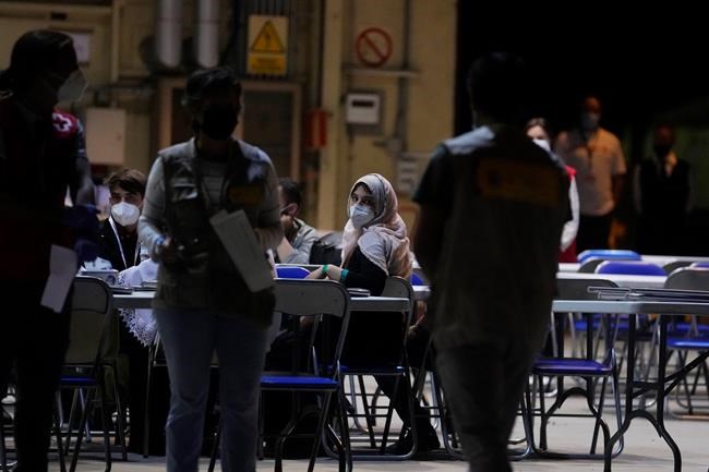 An Afghan woman waits in a COVID testing center after arriving on a Spanish Air Force plane carrying Spanish nationals and Afghans at the Torrejon military base as part of the evacuation process in Madrid, Spain, Thursday, Aug. 19, 2021. (AP Photo/Paul White)