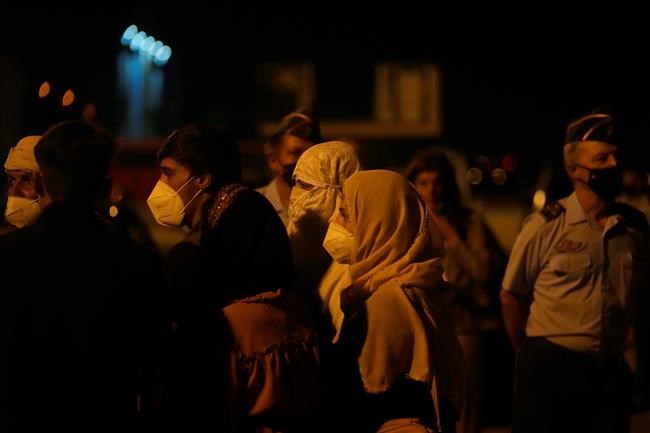 People queue to be tested for COVID-19 after leaving a Spanish airforce plane carrying Spanish nationals and Afghans after it landed at the Torrejon military base as part of the evacuation process in Madrid, Spain, Thursday, Aug. 19, 2021. (AP Photo/Paul White)