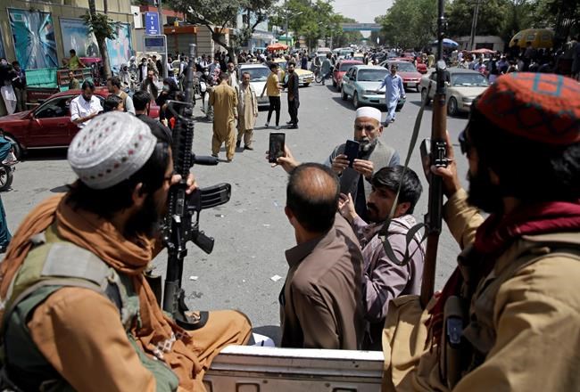 Afghans take selfie wit Taliban fighters during patrol in the city of Kabul, Afghanistan, Thursday, Aug. 19, 2021. The Taliban celebrated Afghanistan's Independence Day on Thursday by declaring they beat the United States, but challenges to their rule ranging from running a country severely short on cash and bureaucrats to potentially facing an armed opposition began to emerge. (AP Photo/Rahmat Gul)