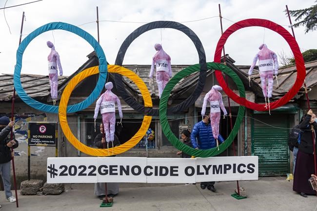 FILE - In this Feb. 3, 2021, file photo, exile Tibetans use the Olympic Rings as a prop as they hold a street protest against the holding of 2022 Winter Olympics in Beijing in Dharmsala, India. Some of the world’s largest broadcasters including American network NBC are being asked to cancel plans to cover the 2022 Winter Olympics in Beijing over alleged human rights abuses in the country. The Games open on Feb. 4. (AP Photo/Ashwini Bhatia, File)