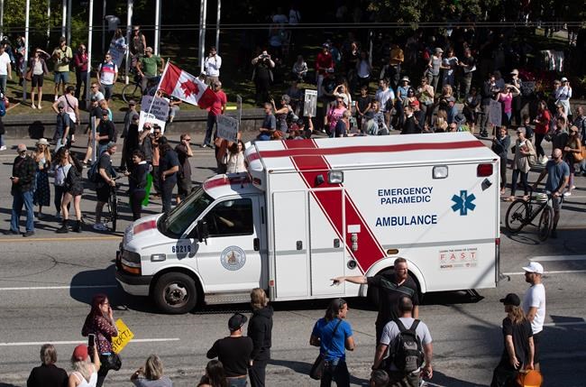 An ambulance passes through a crowd of people protesting COVID-19 vaccine passports and mandatory vaccinations for healthcare workers, in Vancouver, B.C., Wednesday, Sept. 1, 2021. THE CANADIAN PRESS/Darryl Dyck